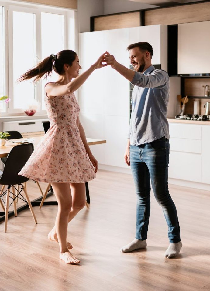 Junges Paar tanzt in der neuen Wohnung auf Mallorca, glücklich über die hilfreichen Tipps zur Kaufberatung